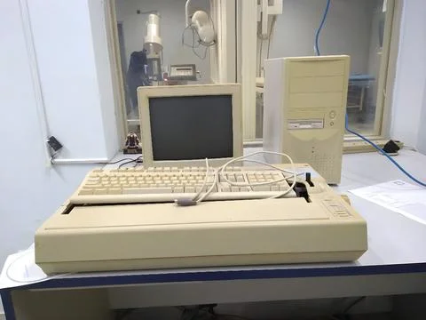 Old and obsolete computer on old wood table with concrete wall background Foto stock