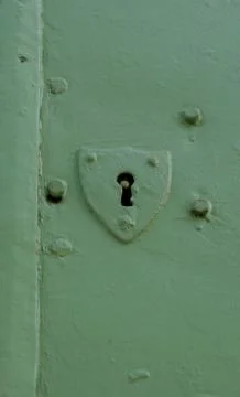 Old and plain shield shaped door key hole on a green door Stock Photos