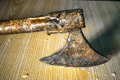 Old and rusty axe hitting a wooden table and water drops on it Stock Photos