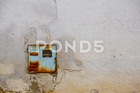 An old and rusty electricity meter fits perfectly in a very deteriorated wall Stock Photos