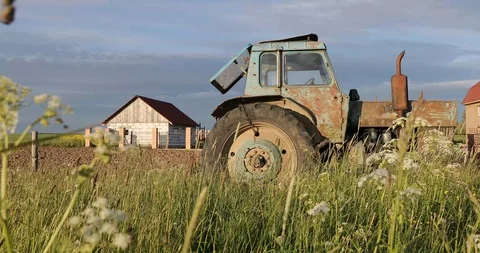 Old and rusty farm machine in the field on the background of the house Stock Footage 111496100