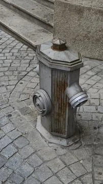 Old and rusty fire hydrant on a cobblestone street Stock Photos