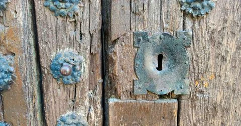 Old and rusty medieval lock on old studded wooden door Stock Photos