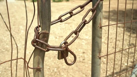 Old and rusty metal chain and lock of a gate on gravel road Stock Footage 107544358