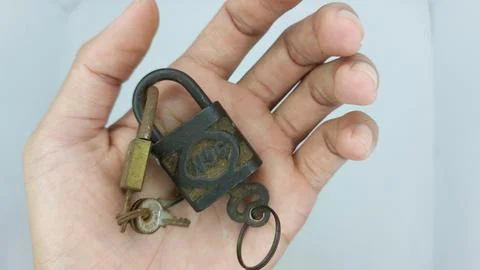 An old and rusty padlock key for securing a house door on a white background Stock Photos