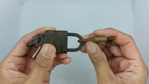 An old and rusty padlock key for securing a house door on a white background Stock Photos
