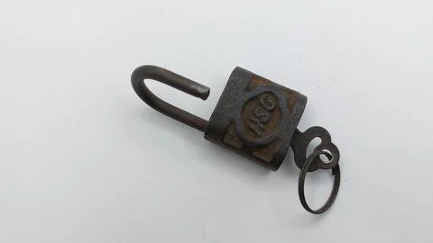 An old and rusty padlock key for securing a house door on a white background Stock Photos