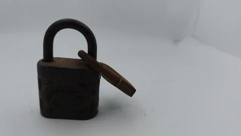 An old and rusty padlock key for securing a house door on a white background Stock Photos