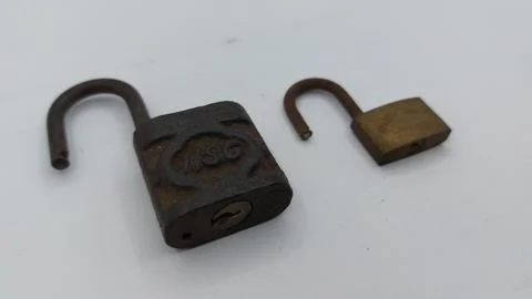 An old and rusty padlock key for securing a house door on a white background Stock Photos
