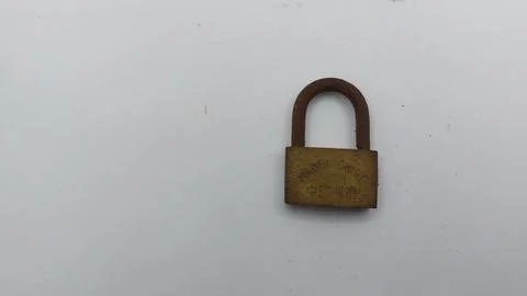 An old and rusty padlock key for securing a house door on a white background Stock Photos