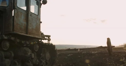 An old and rusty tractor, plowing the agricultural land, sunset. Slow motion. Stock Footage 153378610