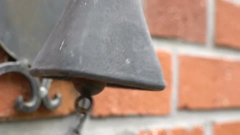 An old, antique, rusty bell hanging on a brick wall.  Stock-Footage 136488313