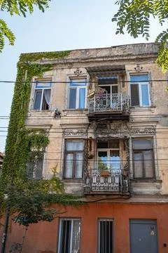 Old apartment building facade with a small balcony and a clear blue sky Stock Photos