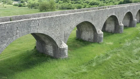 Old arch bridge made of stone over a green grassy field - long vintage viaduct Stock Footage 212127224