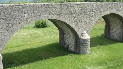Old arch bridge made of stone over a green grassy field - long vintage viaduct Stock Footage 212141047
