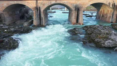 Old arch bridge over blue river flowing through beautiful rocky landscape Stock Footage 211784775