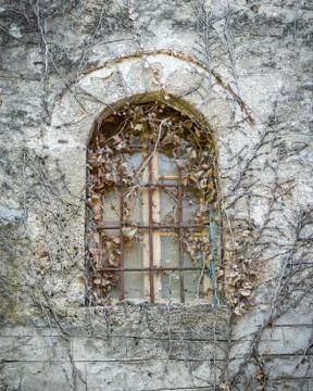 Old arched window on rough stone wall Foto stock