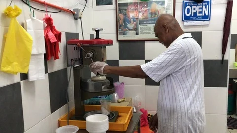 Old asian man using traditional ice shaver to prepare for cold "cendol" drink. Stock Footage 102488156