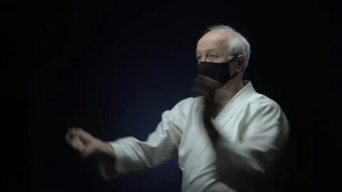 An old athlete makes blocks and punches against a dark background Stock Footage 139134730