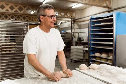 Old authentic baker in bakery making organic bread and taking care of it with 写真素材
