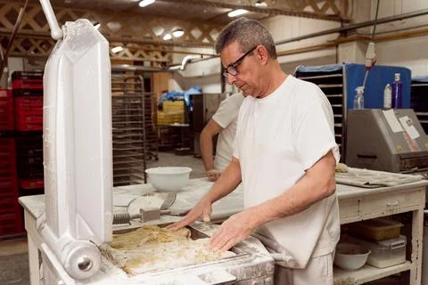 Old authentic baker in bakery making organic bread and taking care of it with 스톡 사진