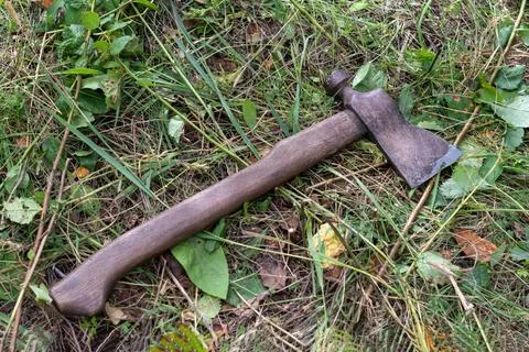 An old axe is lying on the grass in the garden Stock Photos