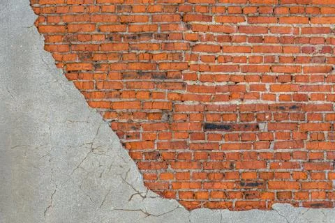 Old bad brick wall with leftovers of gray peeled thick sandy plaster Фото