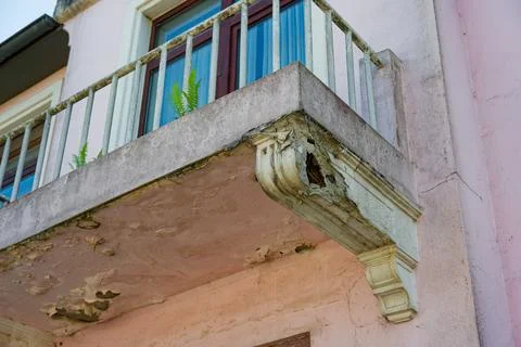 Old balcony underside with exposed rebar and crumbling concrete decay. Stock Photos
