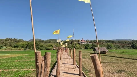 Old Bamboo Bridge with Buddhist Flags and Rice Fields in Northern Thailand Video stock 339983096