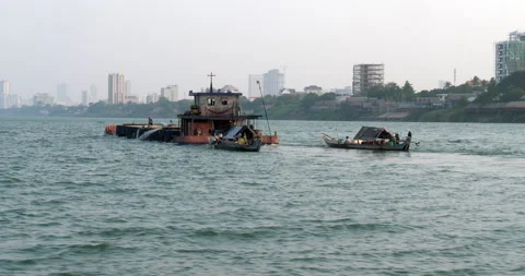 Old barge loaded with sand pulling two small motorboats on a rippling river.  Stock Footage 268916590