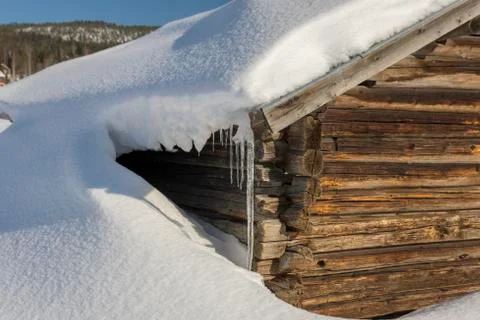Old barn with one side covered with snow and with a icicle from the roof Stock Photos