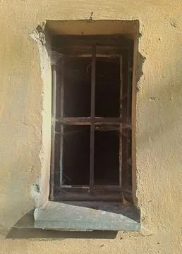 Old barred window in a weathered plaster wall. Stock Photos