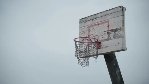 Old basketball hoop with torn net hanging in wind and peeled off paint Stock Footage 105366154