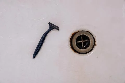 Old bath drain, disposable razor, white background Stock Photos