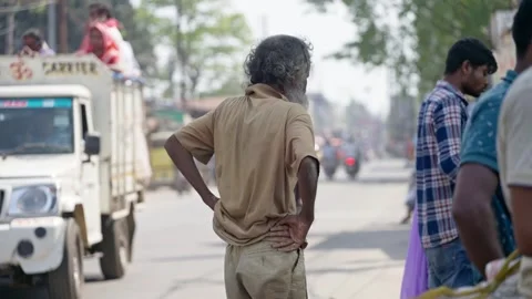 An old begger Indian Man With Long Beard Standing On Busy Summer Street with Stock Footage 332896539