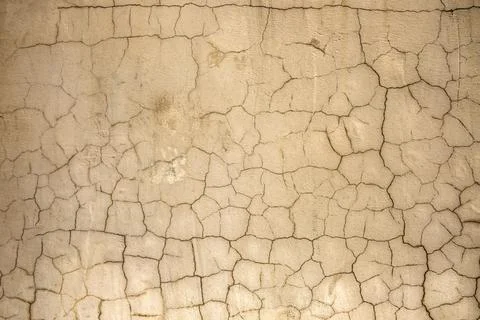 Old beige wall with dark cracks. rough surface texture Stock Photos