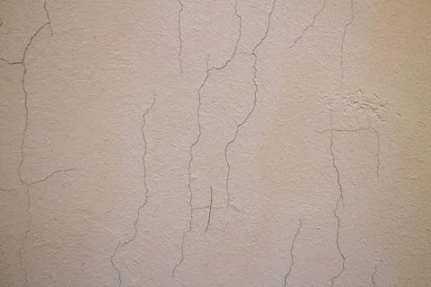 Old beige wall texture with vertical cracks and weathered plaster surface Photos