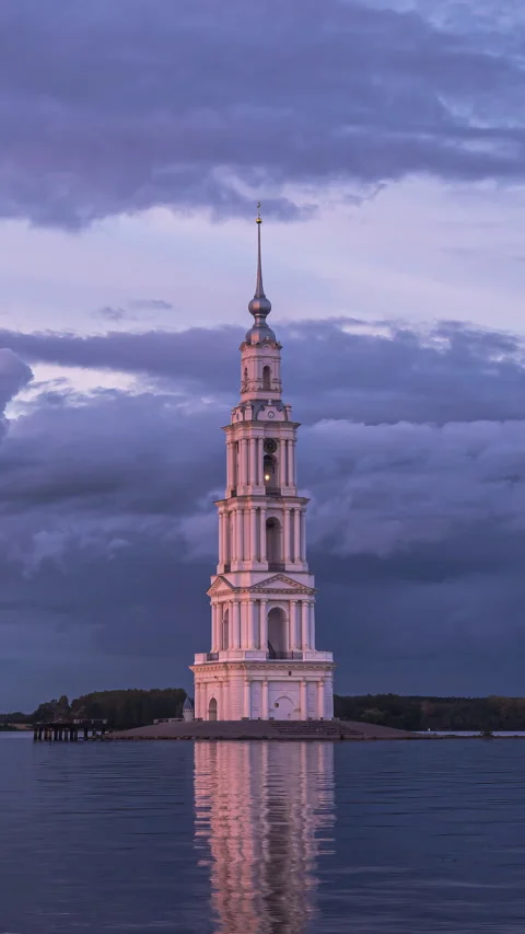 Old bell tower in middle of  lake. Time lapse of dramatic evening cloudy sky Stock Footage 293950318
