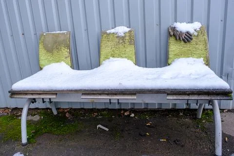 An old bench with backs against the wall of the building is covered with snow Fotos de archivo
