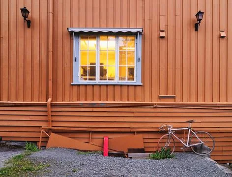 An old bicycle under the window of a house with lights on Stock Photos