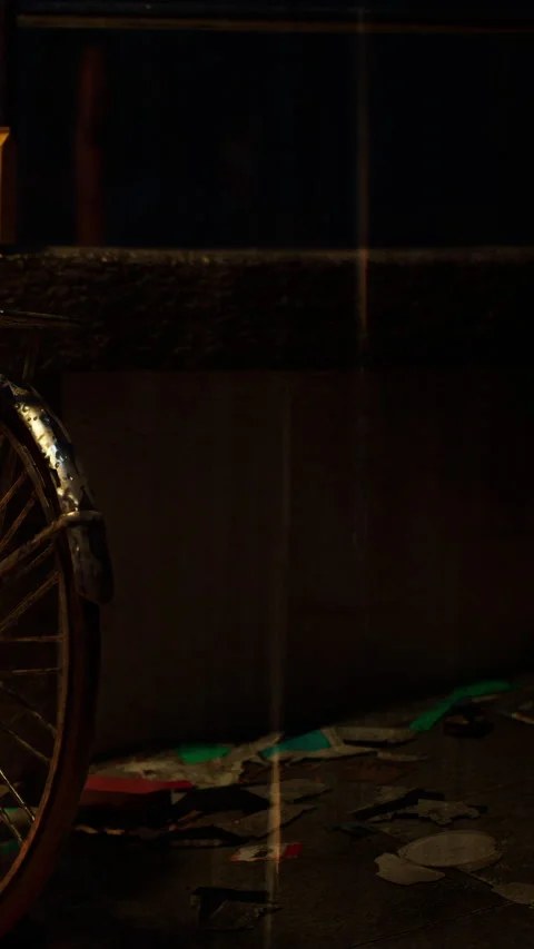 Old bicycle wheel rests on the ground next to scattered papers at night Stock Footage 338346855