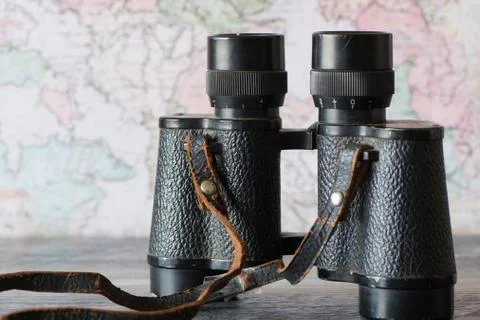 Old binoculars with strap against map. Retro travel Concept Stock Photos