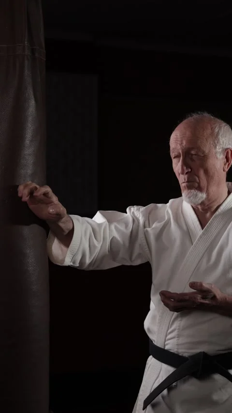 An old black belt trainer performs side punches on a machine Video stock 309742014