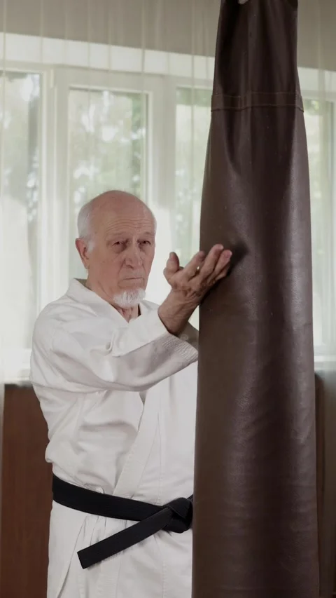 An old black belt trainer throws circular punches on a machine Stock Footage 309742001