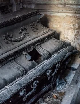 Old black coffin with a hole in a tomb Stock Photos