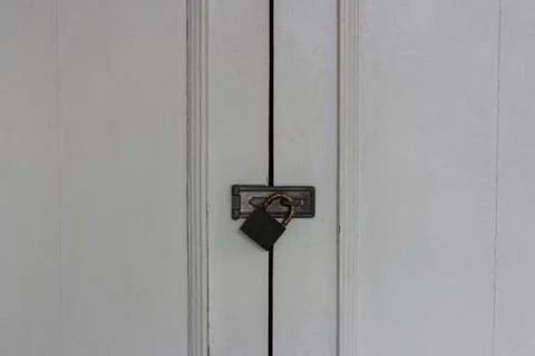 Old black padlock with rust on old white wooden door. Stock Photos