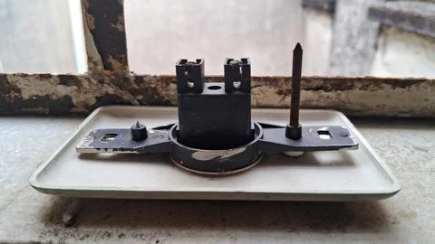 Old black plastic electrical light switch plate with rusty iron spike Stock Photos