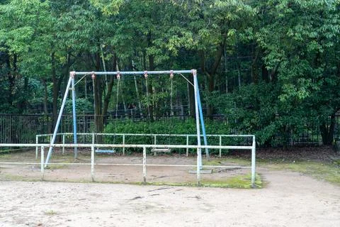 Old blue rusty swing set in an empty rural park playground 스톡 사진