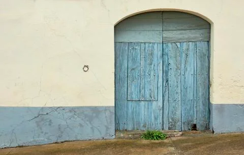 An old blue wooden door and a ring to tie the horses to the wall next to it. Stock Photos