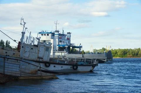 The old boat and the ferry at the shore on the river on a sunny summer day. Stock Photos